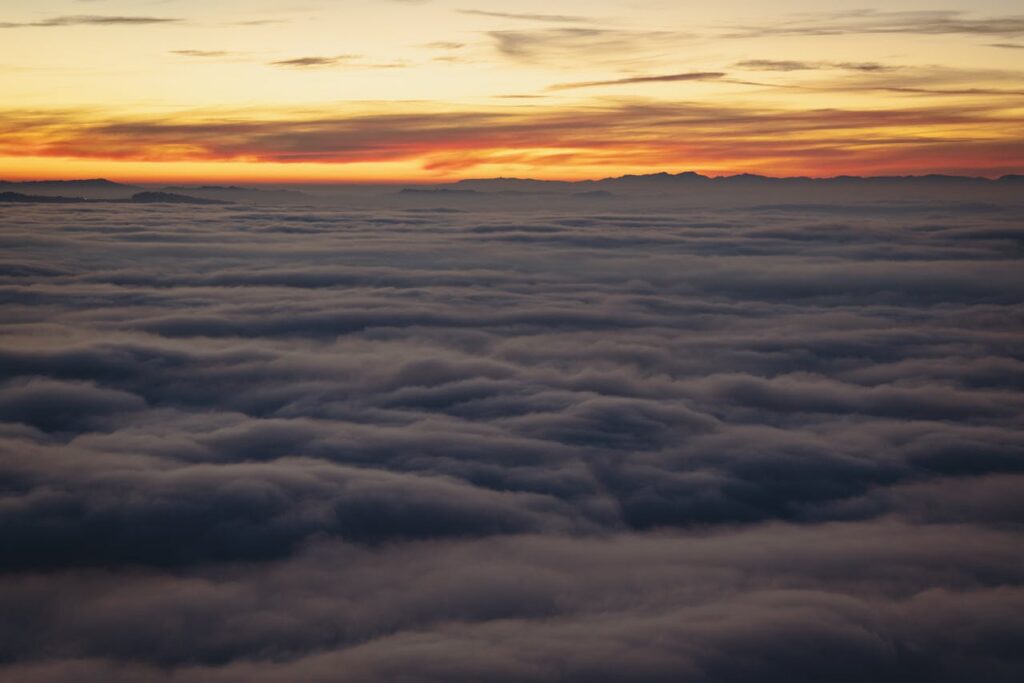 A breathtaking view of a vibrant sunset above a thick cloud layer, creating a serene atmosphere.